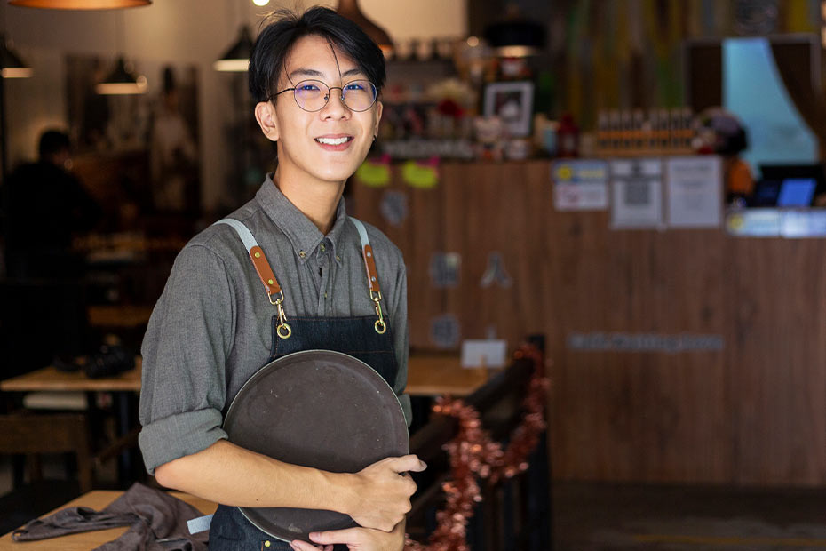 A young server standing in front of a restaurant