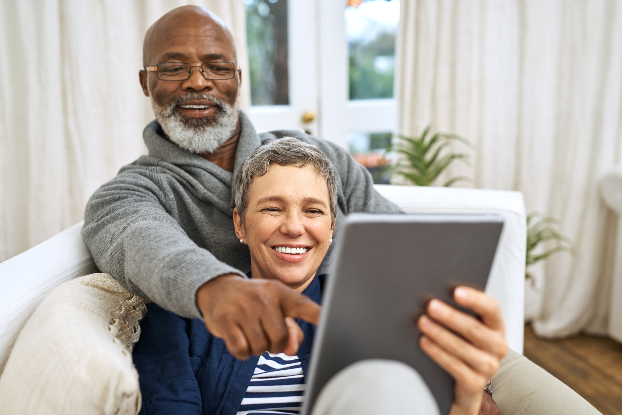 Cropped shot of an affectionate senior couple using a tablet while relaxing on the sofa at home