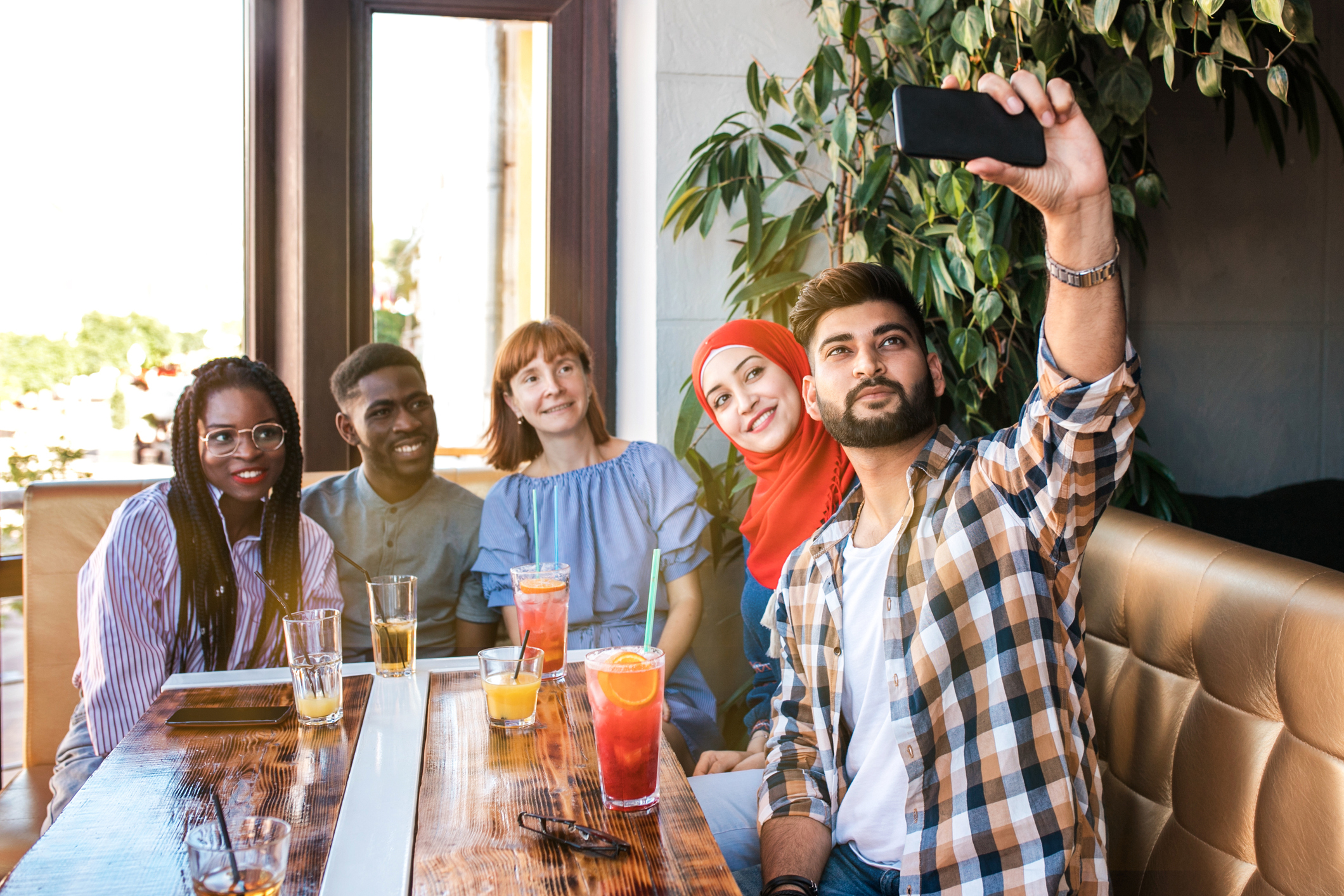 Group of happy friends making selfie on smartphone together in cafe. Friendship and youth concept.