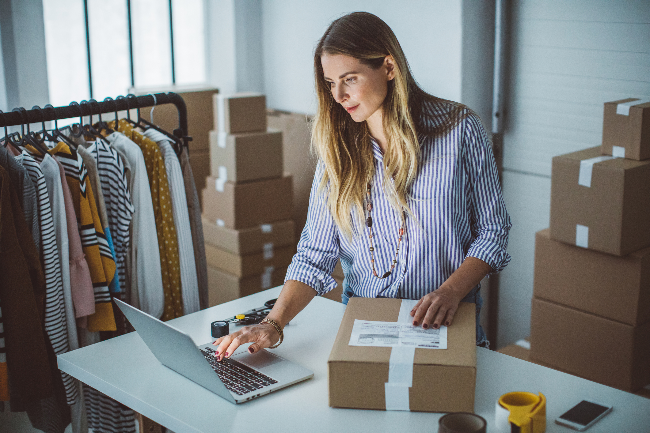 Women, owener of small business packing product in boxes, preparing it for delivery.