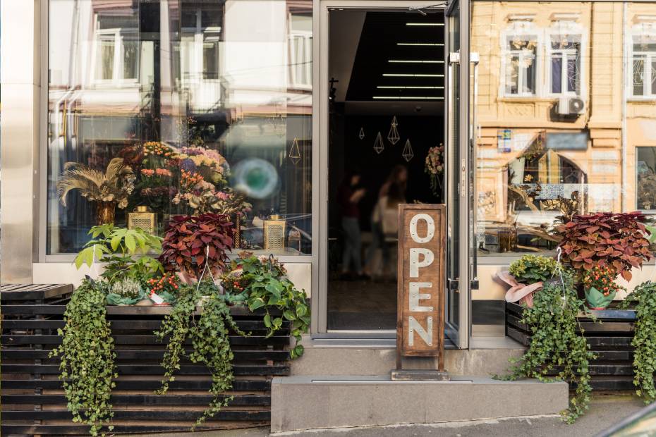 A small business from the outside with an "Open" sign and customers inside