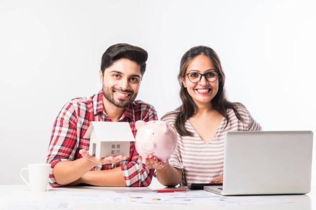 Focused Indian young newcomer couple accounting, calculating bills, discussing planning budget together using online banking services