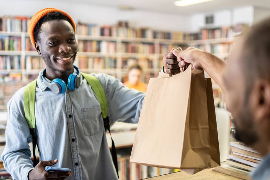 A cashier passes a bag to a customer in a store.