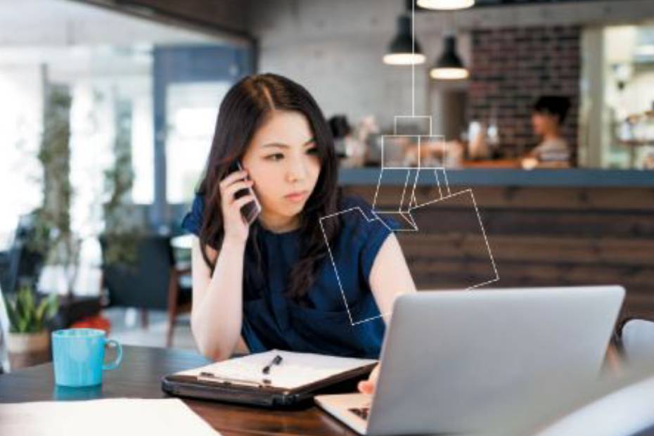 Lady making a call on her phone and also scrolling on her laptop.