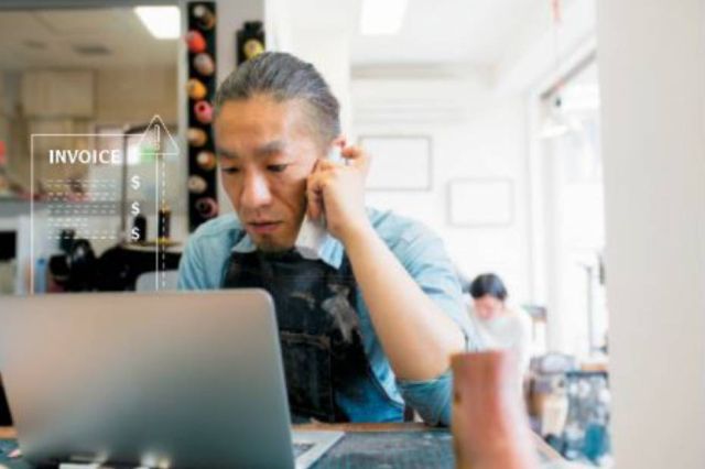 Man making a call on his phone while scrolling on his laptop