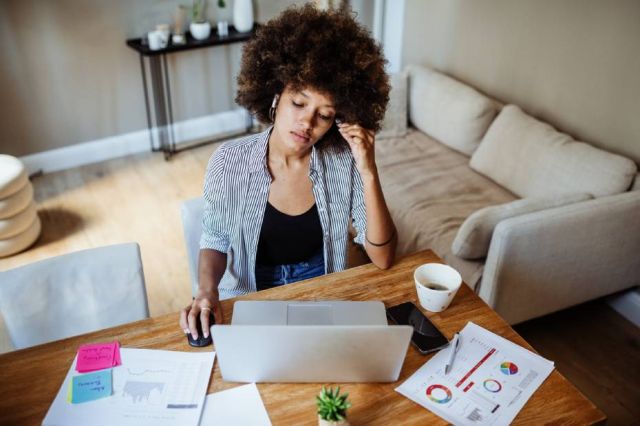 A woman by her table with a laptop and papers