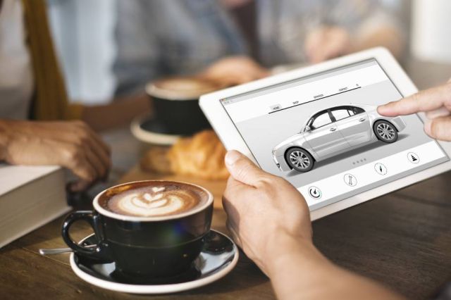 A driver in a coffee shop, researching electric vehicles on a tablet