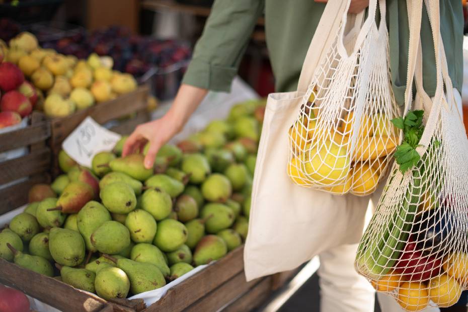 A shopper reduces single-use plastic waste by bringing their own bags and buying packaging-free produce.