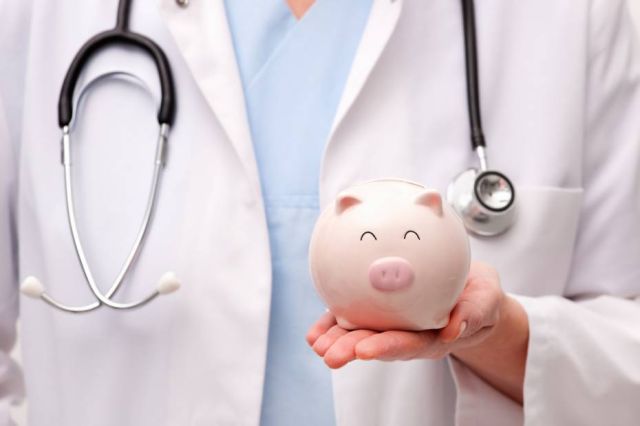 A picture showing a female physician holding a piggy bank on her hand.