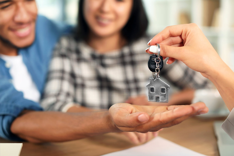 New home buyers on the closing day for their first home, receiving the keys from the real estate agent after reviewing closing documents.