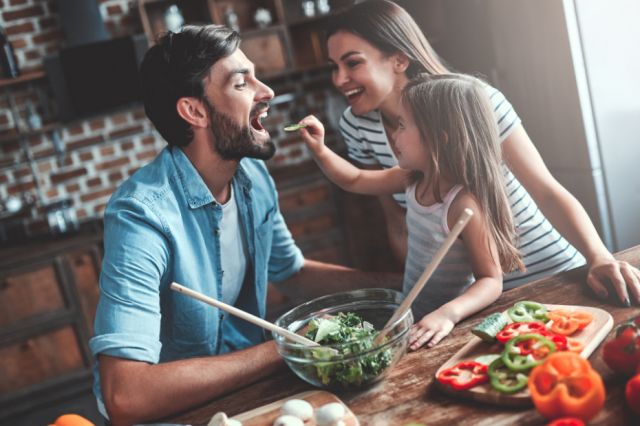 A father, mother & daughter making dinner in the kitchen together.