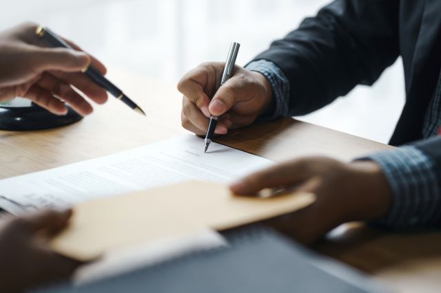 Legal support with an individual signing papers at a desk