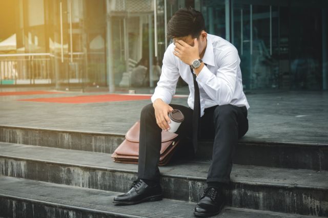 Unemployed businessman stress sitting on stairs outside office