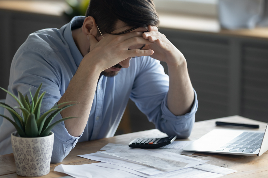 Distressed young Caucasian man sit at desk paying bills