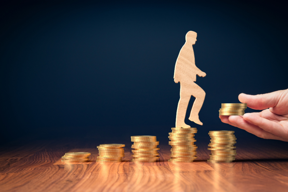 A wooden cut out of a person stepping on increasing columns of coins with a helping hand adding more money