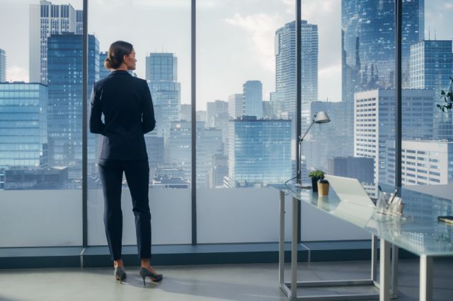 Stylish woman looking confidently out the window at the big city below.