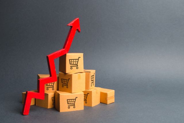 Stack of cardboard shopping boxes and a red up arrow showing rising interest.