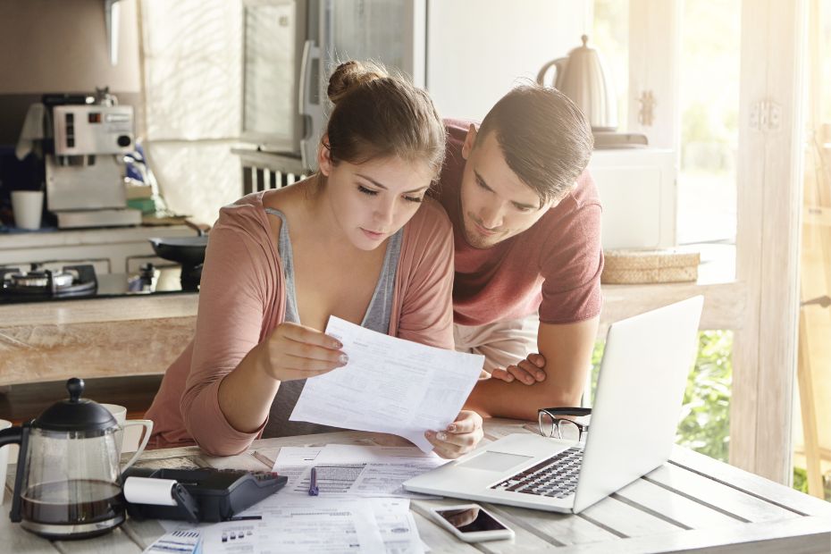 Young couple doing paperwork together, paying taxes online on laptop