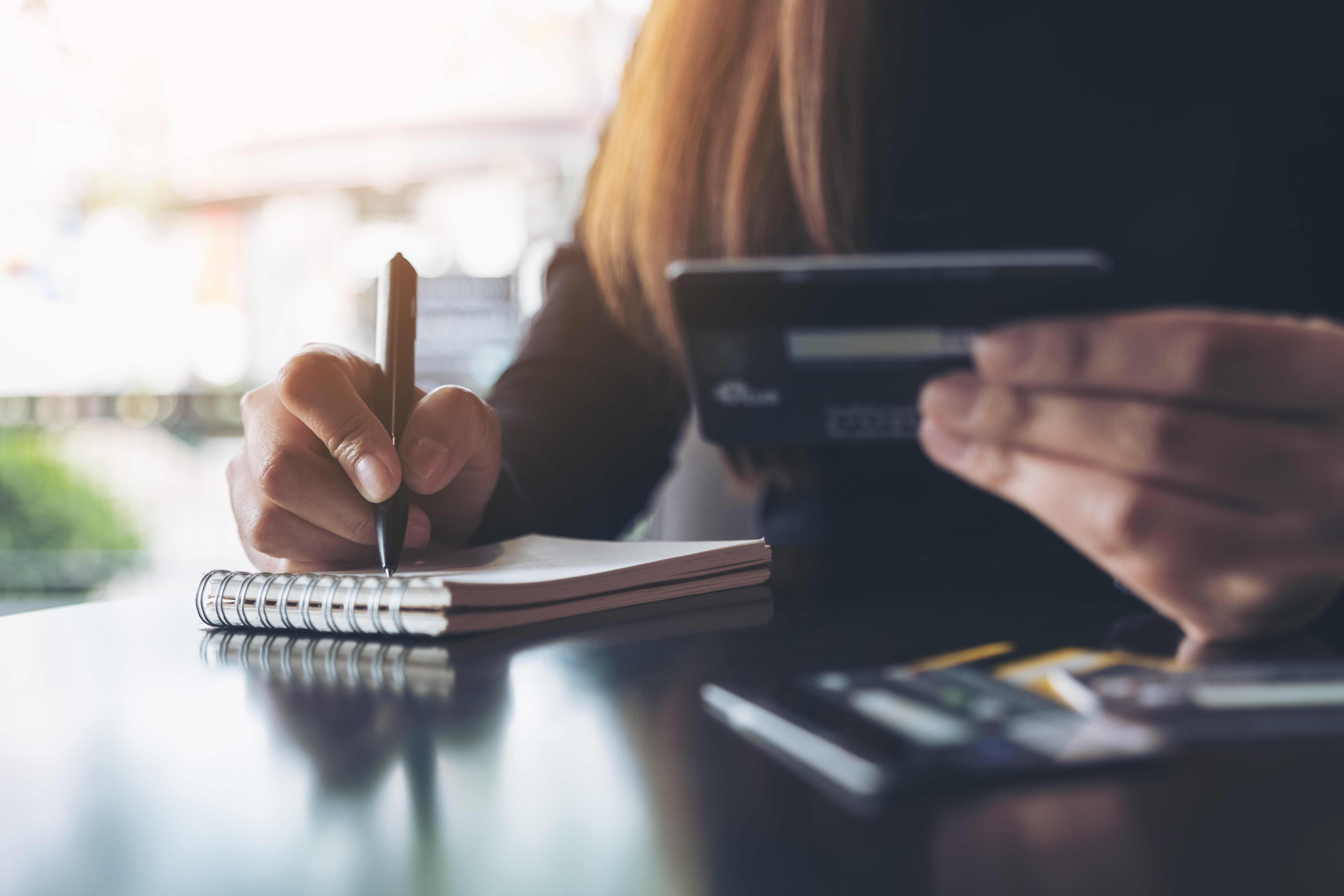 Une fille écrivant sur un bloc-notes et utilisant une calculatrice.