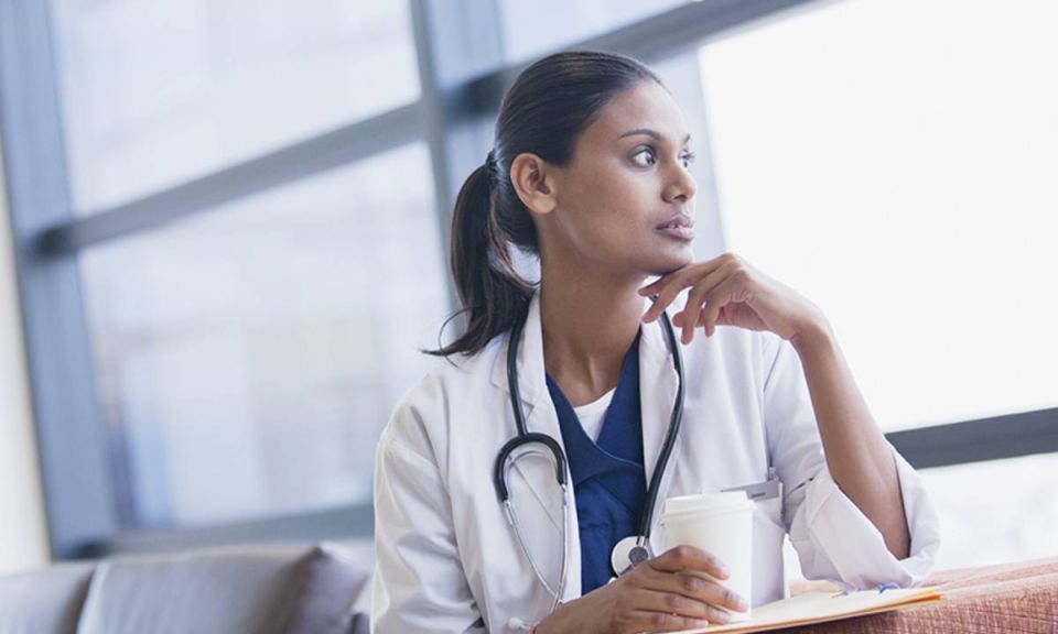 Image d'une jeune médecin regardant pensivement par la fenêtre.