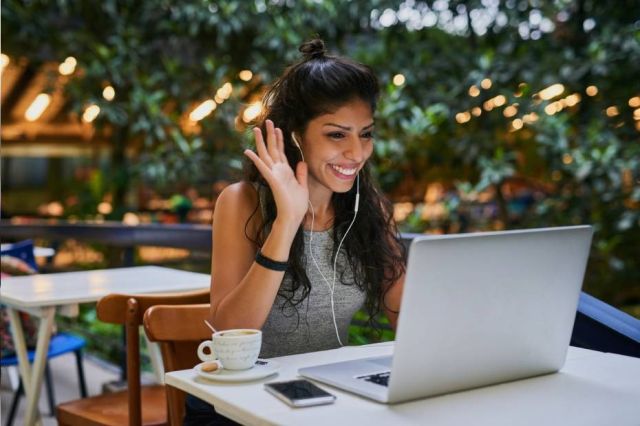 Femme agitant et souriant à l'ordinateur portable