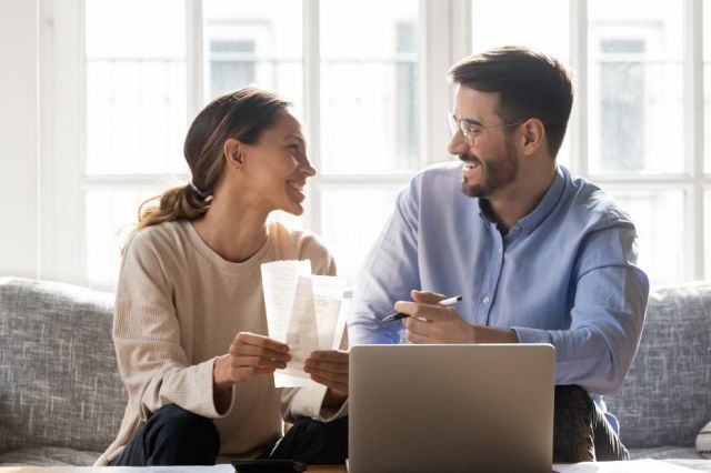 Un couple souriant sur un canapé, travaillant à un budget