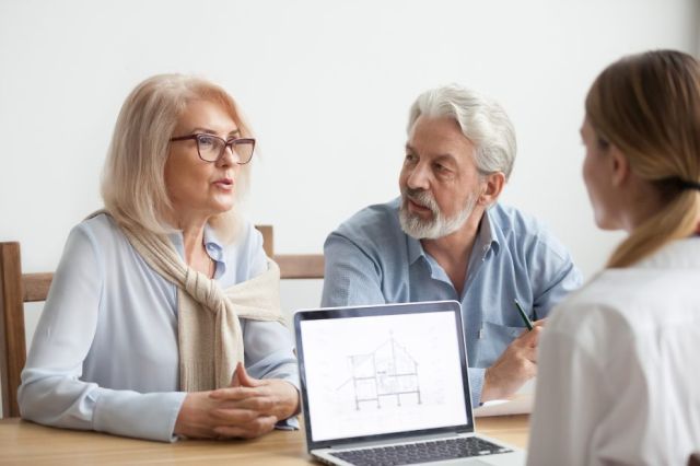 Un couple d'aînés discute de plans de rénovation avec un conseiller.