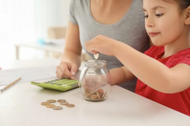 Jeune fille et sa mère qui comptent de l'argent à une table.