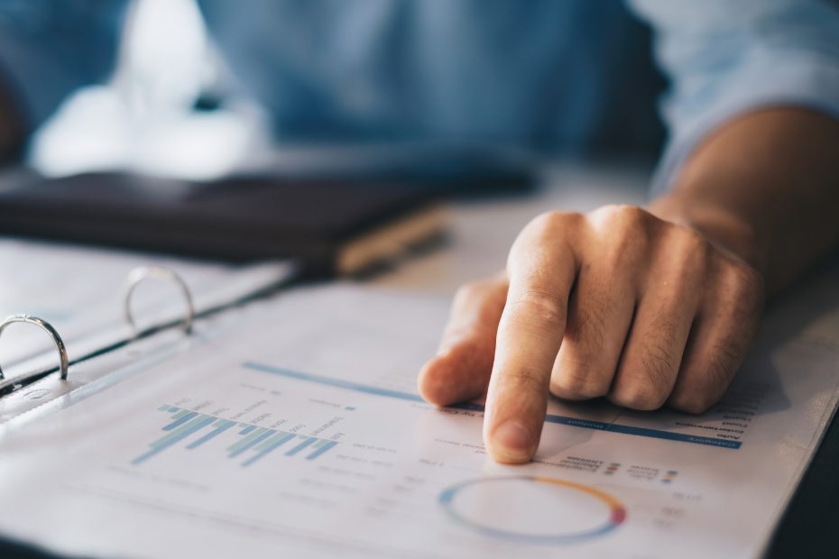 Un homme, hors de l'image, assis à son bureau, avec une main pointant vers un diagramme circulaire