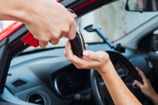 Main d'homme tenant une clé d'auto sur fond de stationnement flou